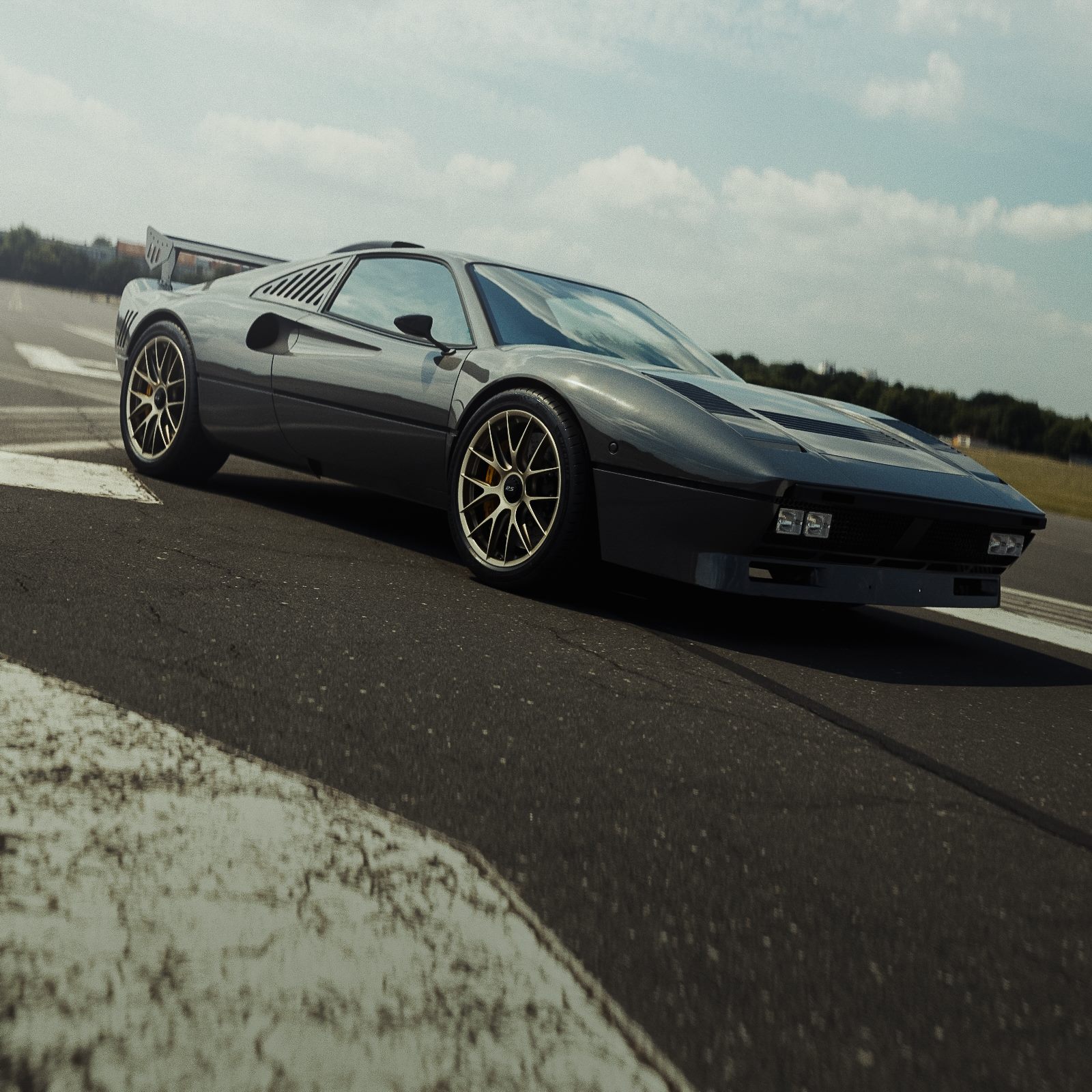 Dark grey 288 GTO sports car on a track under a cloudy sky