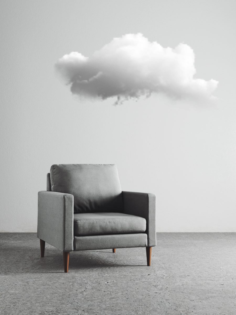 Grey armchair on a concrete floor with a small cloud floating above it