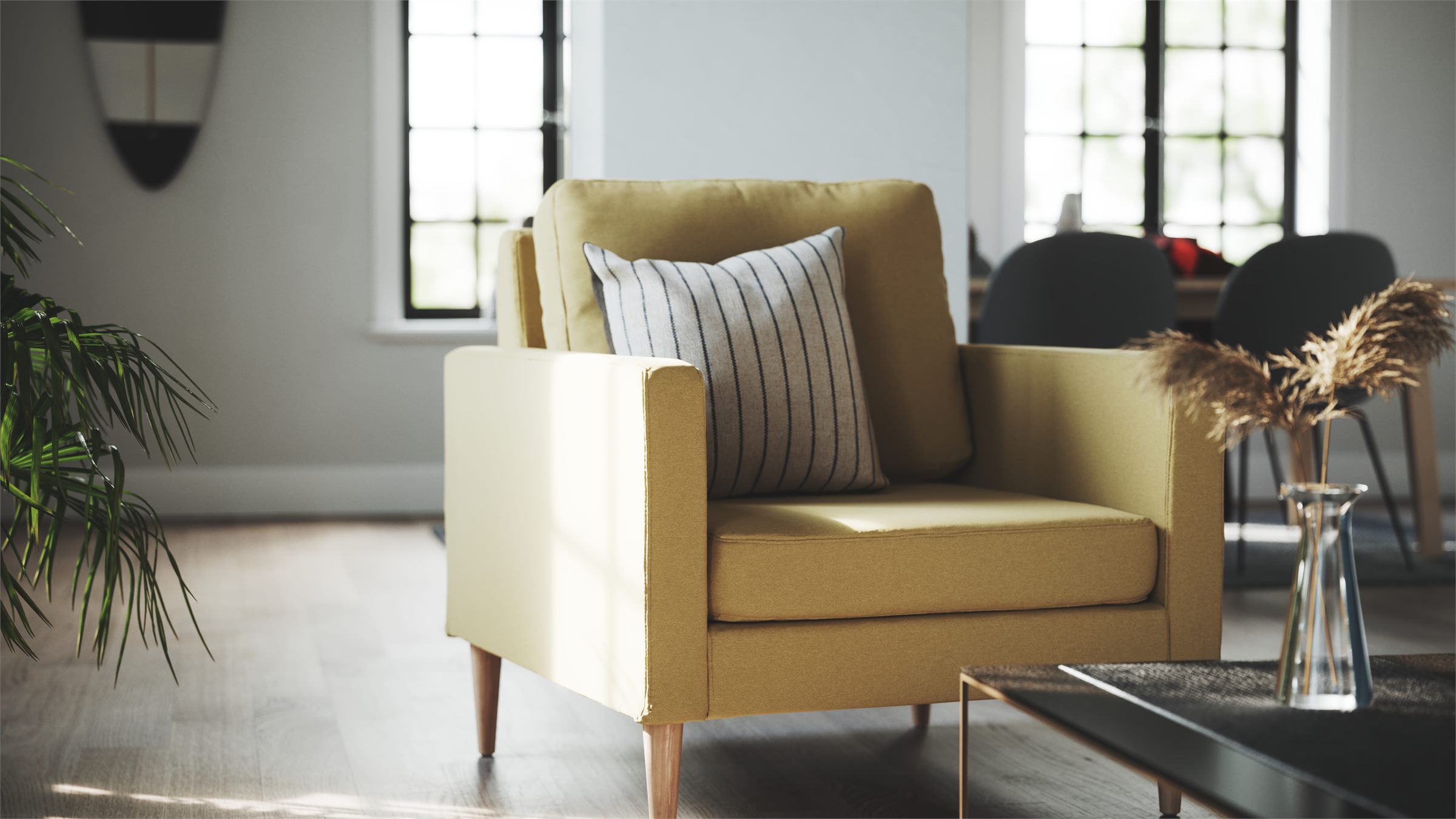 Yellow armchair with a striped cushion beside a glass vase with dried grasses