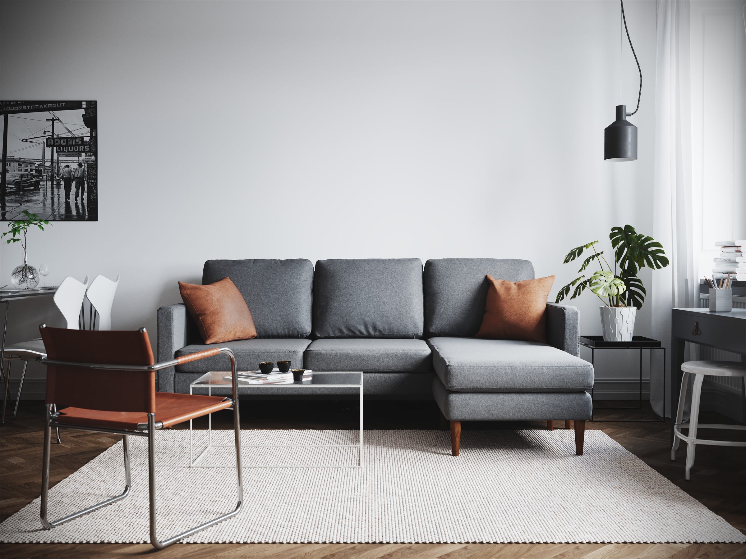 Living room with a grey sectional sofa, orange cushions, a leather chair and a light rug