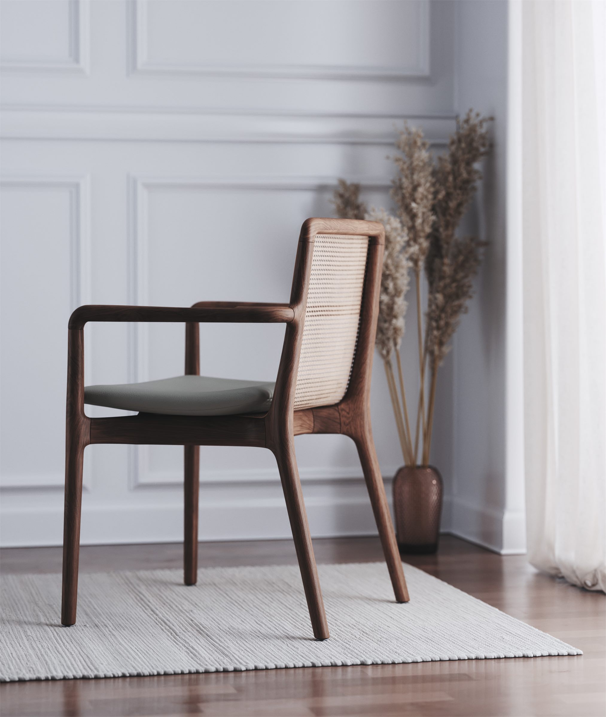 Wooden chair with a woven back and a green seat on a rug beside a vase of dried grasses