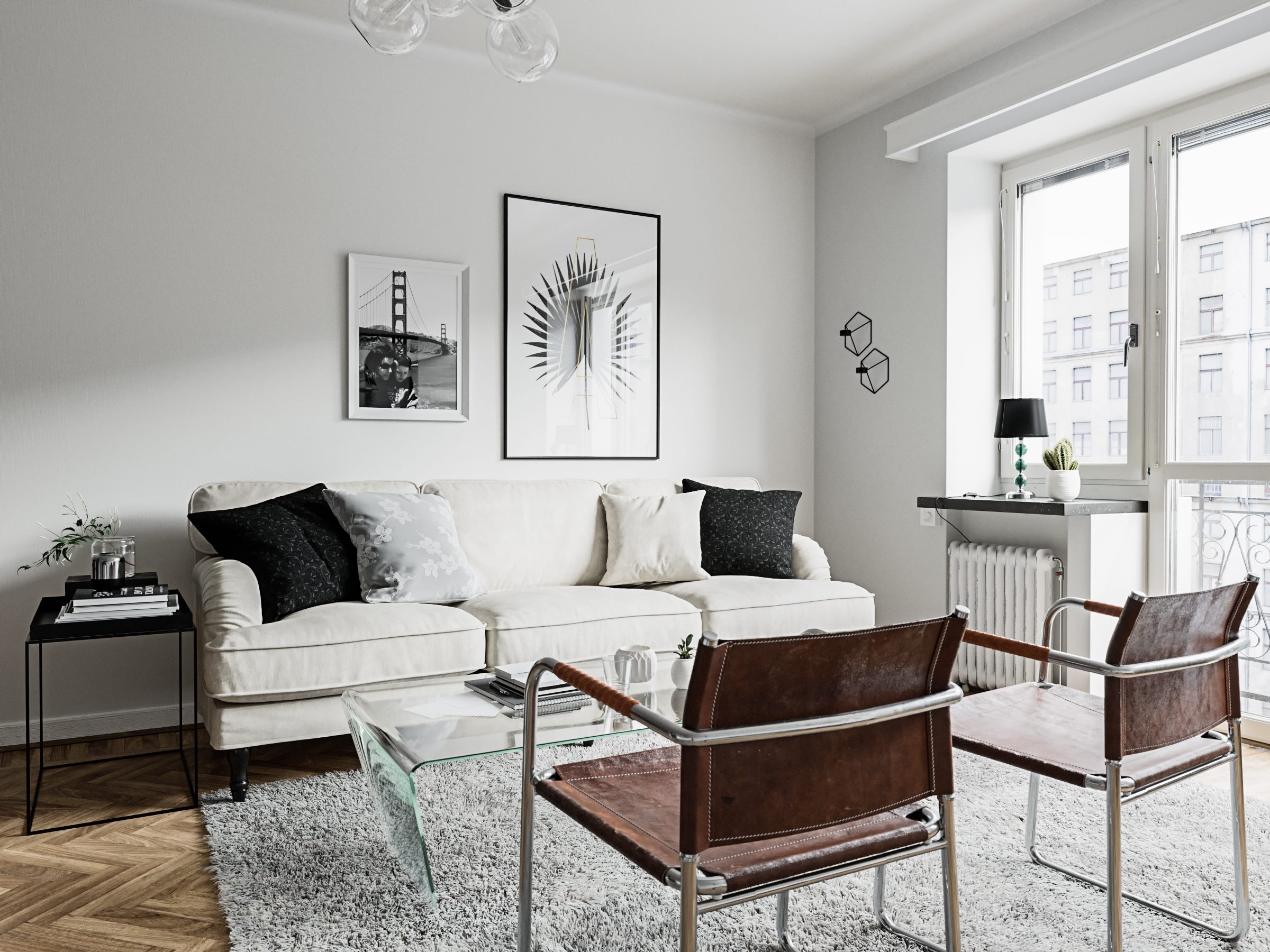 Living room with a white sofa, two leather and steel chairs, a glass coffee table and framed prints