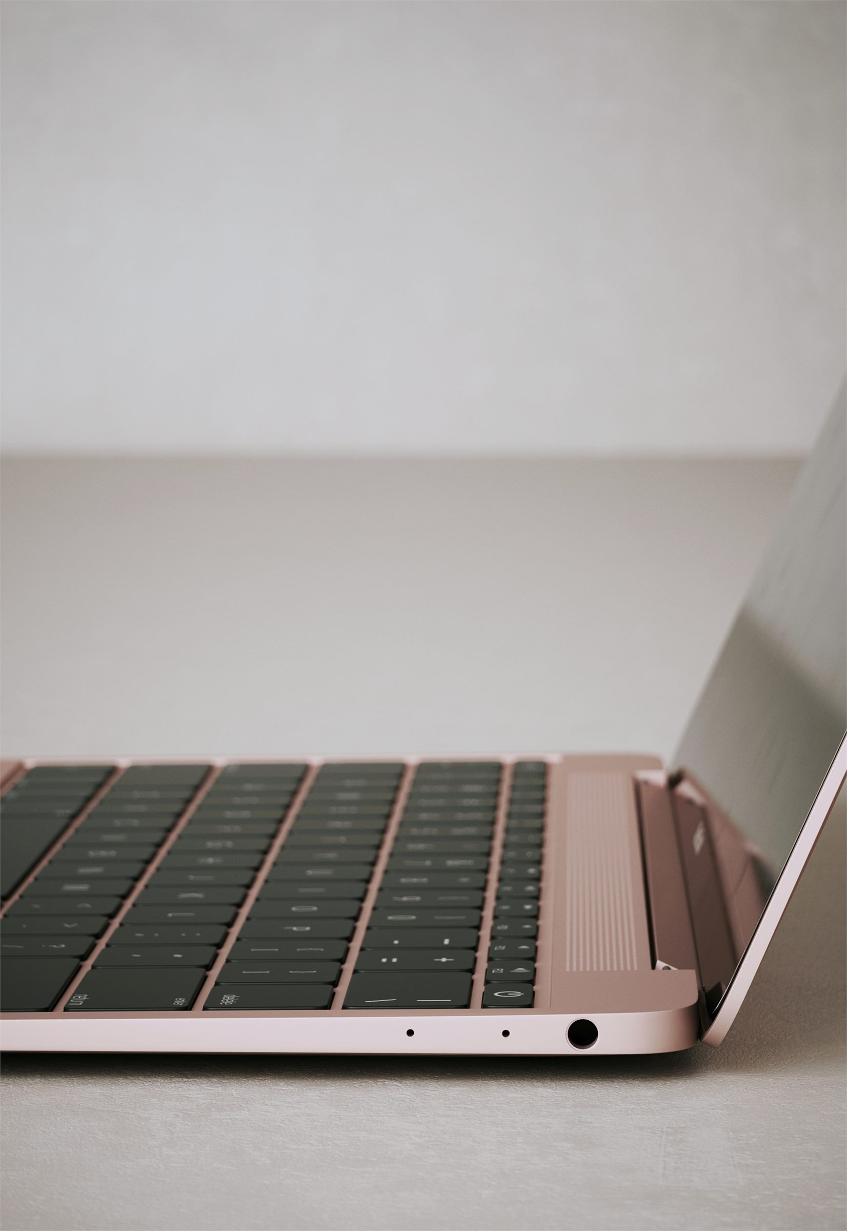 Close-up of the keyboard and side ports of a rose gold laptop