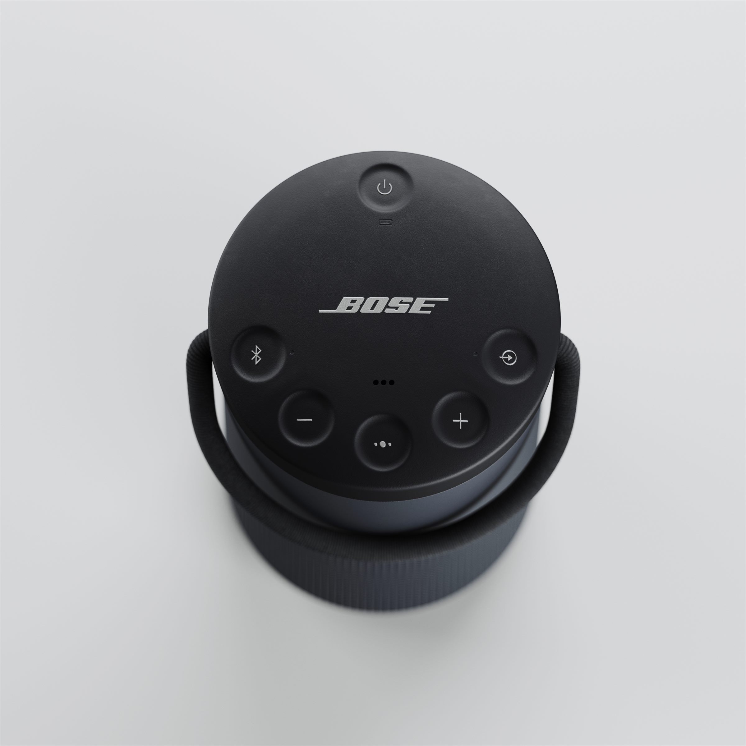 Round black portable speaker with a handle, seen from above