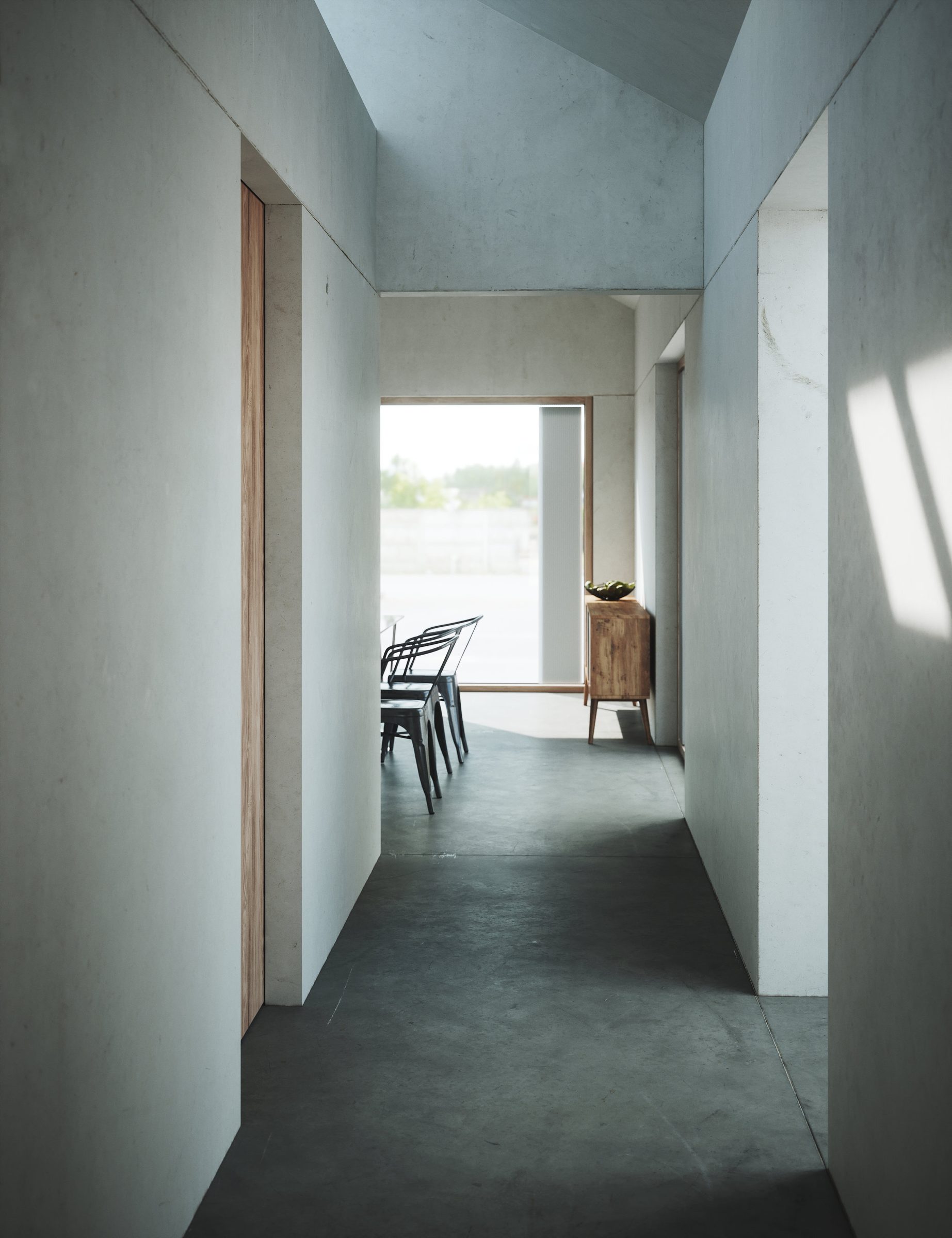 Corridor with a concrete floor and pale walls leading to a dining area